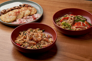 A variety of delicious dishes, including potato pancakes with bacon and mushrooms, stir-fried udon noodles with chicken, and fried rice with shrimp.
