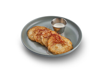 A plate of golden brown potato pancakes (deruny) served with a dollop of sour cream.