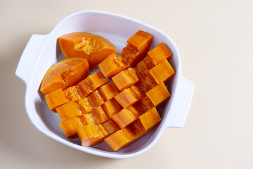 Papaya slices in white ceramic bowl with copy space. Top view ripe papaya on beige background. Freshness, fruit, eating healthy, lifestyle, harvest, vegan concepts. Prepare papaya fruit in bowl.