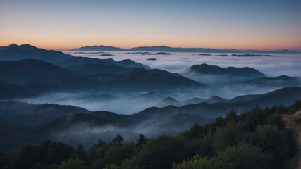A breathtaking panorama of mountains and a foggy valley just after dawn offering a dreamy landscape.