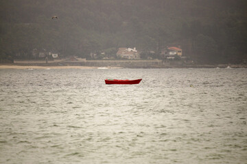 Fototapeta premium Red Boat Floating on Calm Ocean Waters in Fog