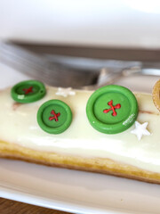 Green and red button is on a white cake