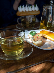 Plate of pastries sits on a wooden table next to a cup of tea