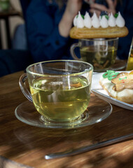 Cup of tea sits on a wooden table next to a plate of pastries