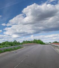 Road with a bridge in the background and a cloudy sky