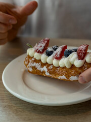 Person is holding a pastry with strawberries and blueberries on top