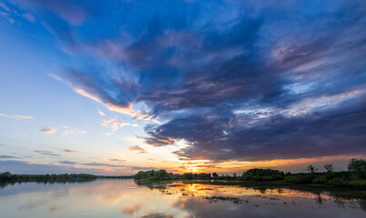 Obraz premium Beautiful sunset over a lake with a few clouds in the sky