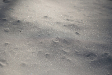 dettagli della superficie di un terreno naturale coperto dalla neve con forme variabili disegnate dal vento ed illuminate dal sole, di giorno, in inverno
