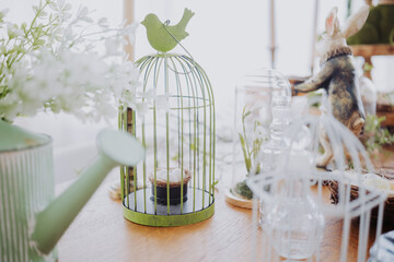 Decorative birdcage centerpiece with flowers on wooden table in bright room