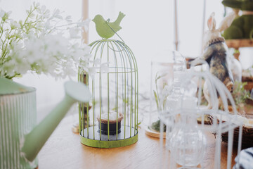 Decorative green birdcage with plants and gardening tools on a wooden table