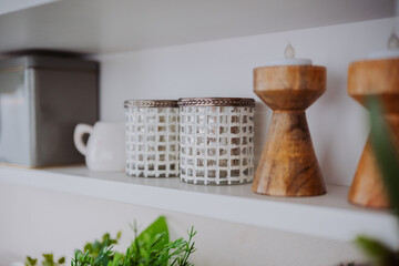 Decorative items on a shelf with glass jars, candles, and greenery