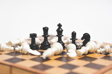 Black chess pieces defeating a white pawn lying on a white background