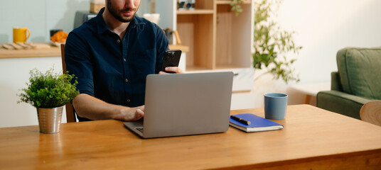 Man using laptop while sitting at home. Young woman sitting in kitchen