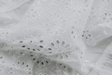 Delicate white fabric with intricate embroidery details in soft sunlight