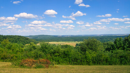 Vast countryside, green forests, rolling hills. Natural idyll, summery.