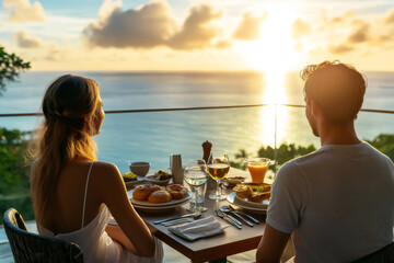 Romantic couple enjoying breakfast with a breathtaking ocean view during a vibrant sunset