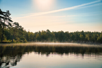 Fototapeta premium Sunrise with fog forming over a lake in Sweden, at dawn. Romantic silence