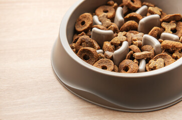 Dry dog food in a slow feeder bowl placed on a wooden surface