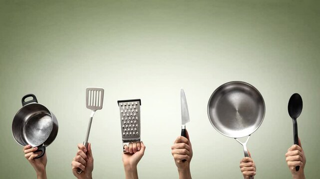 Multiple hands holding various kitchen utensils with a playful wiggling motion