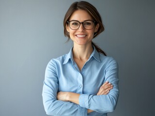 Smiling, professional woman in office environment, confident posture with arms crossed.