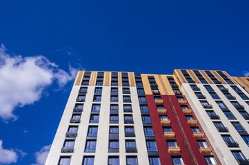 The exterior of a modern multi-storey residential building - facade, windows and balconies against the sky