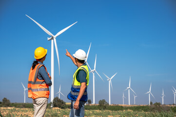 Japanese engineer man working with Asian female wind turbine technician in wind energy plant 
