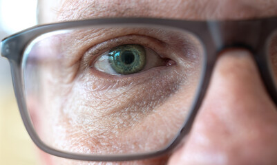 Close-up of a male face with eye, through spectacle lens.