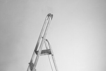 Metal ladder stands against a plain wall during a home renovation project © reddish