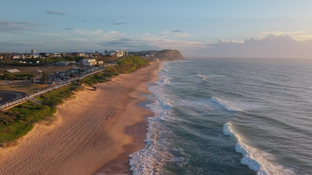 Aerial establishing dolly along Merewether Beach to Bar Beach, ocean waves and coastal beauty at golden hour