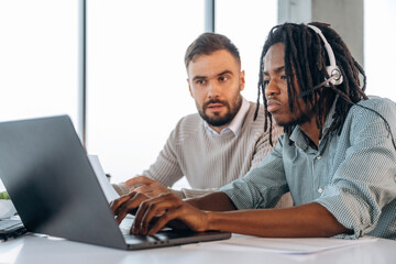 Typing on keyboard of laptop. Two men are working in the office