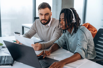 Typing on keyboard of laptop. Two men are working in the office