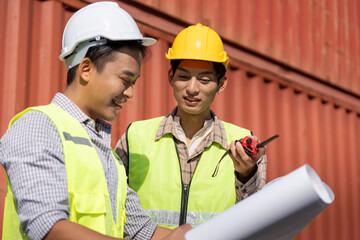 Engineers discussing logistics and construction plans with blueprints and a walkie-talkie.