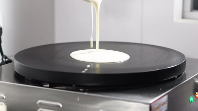 Close-up of a chef pouring batter onto a professional pancake pan. Concept of recipes and cooking process.