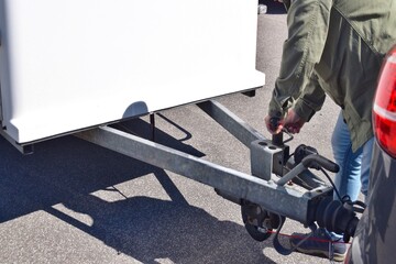 A man attaches a trailer to a car.