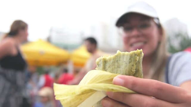 Close-up of woman Enjoying green tamale in market farm, Peruvian street food.