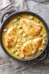 Chicken breast diane in spicy creamy mustard sauce with mushrooms  in the skillet on a wooden board. Vertical top view from above