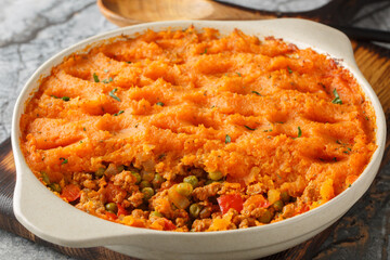Low calorie Sweet Potato Shepherd's Pie with Turkey and Vegetables close-up in baking dish on wooden board. Horizontal