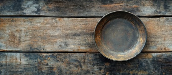 Rustic wooden table with a weathered texture beneath a vacant bronze plate centered in the image showcasing minimalism and natural beauty.