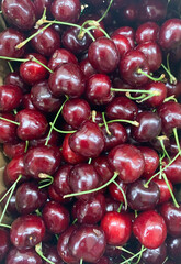 Fresh ripe cherries with vibrant red color and glossy surface, stems attached, arranged closely in a natural pile, showcasing their juiciness and rich texture.