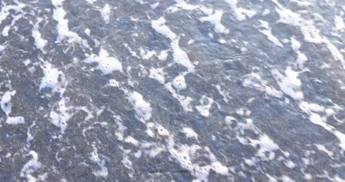 Gentle ocean waves erase word Age written on wet sandy beach edge in summer. Concept of relentless and inevitable passage of time slow motion