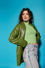 Stylish young woman in green outfit posing against bright blue backdrop