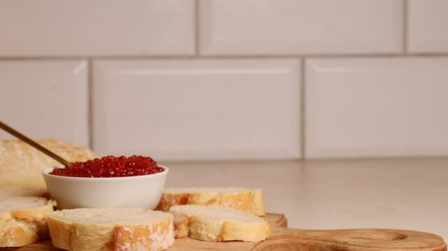 Placing golden spoon in bowl with red caviar. Preparing red caviar sandwich on festive table. Luxurious appetiser elegance and celebration. 