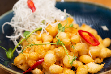 Shrimps in crispy dough with chili and microgreens in a plate, closeup.