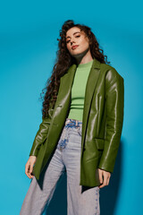 Stylish young woman poses confidently against a vibrant blue backdrop with effortless charm