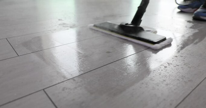 Professional cleaner sanitizes floor tiles using powerful steam mop. Effectively removing dirt and eliminating harmful bacteria with viruses
