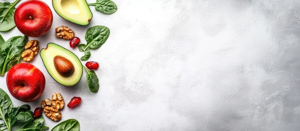 Poster colorful fruit salad featuring red apples, avocado, spinach, and walnuts arranged on a light gray ba