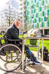 Young disabled man enjoying a drink with friend in city cafe