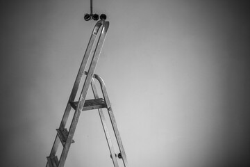 Metal ladder positioned under ceiling with light fixtures in a workspace