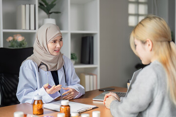 Compassionate Muslim female doctor discussing health concerns with a patient in her modern office,...