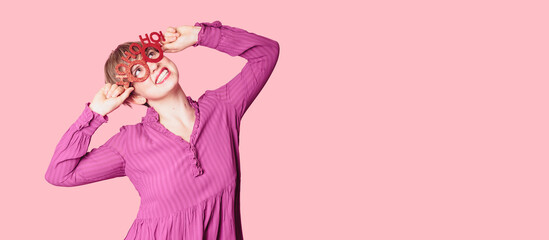 A beautiful young woman with festive New Year's joy, wearing Christmas glasses on a bright background with a place for text